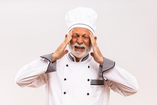 Image of tired senior chef having headache.
