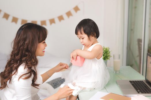 Happy family, beautiful young mother with her adorable little daughter open gift box