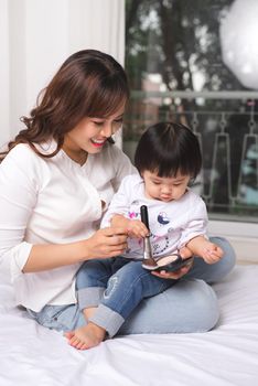 Lovely princess is applying the make up on her skin with special brush as she wants to look like her adult mother