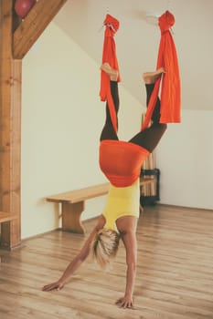 Woman doing aerial yoga in the fitness studio.Image is intentionally toned.