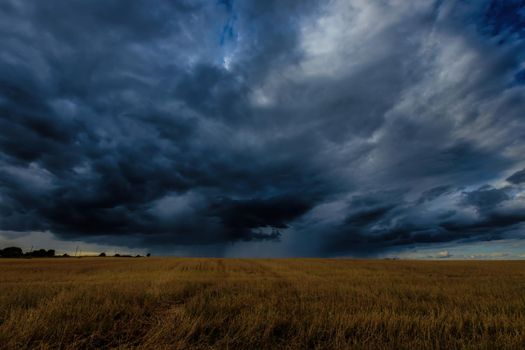 Dark storm clouds in an agricultural field in autumn. An impending storm, hurricane or thunderstorm. Bad extrime weather.