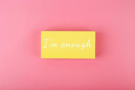 I am enough concept on bright pink background. Lettering design for positive, motivation quote written on yellow rectangle on pink background