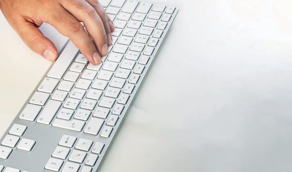 a male hand typing on a modern computer keyboard. Work and employment. Copy space. Wireless technology