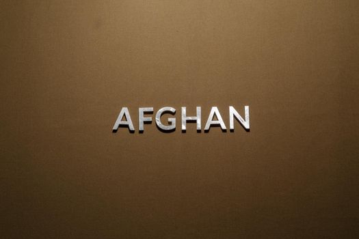 the word afghan laid with silver metal letters on tan khaki canvas fabric