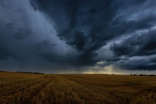 Dark storm clouds in an agricultural field in autumn. An impending storm, hurricane or thunderstorm. Bad extrime weather.