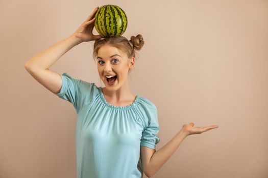 Cute playful woman holding  watermelon on her head and gesturing.Toned image.