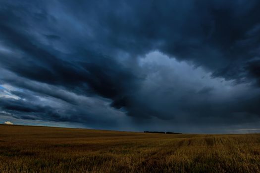 Dark storm clouds in an agricultural field in autumn. An impending storm, hurricane or thunderstorm. Bad extrime weather.