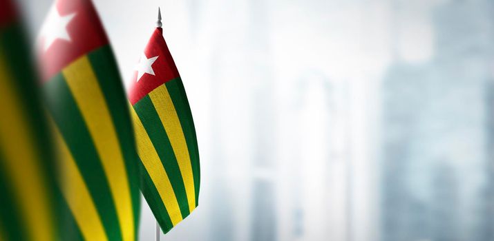 Small flags of Togo on a blurry background of the city.