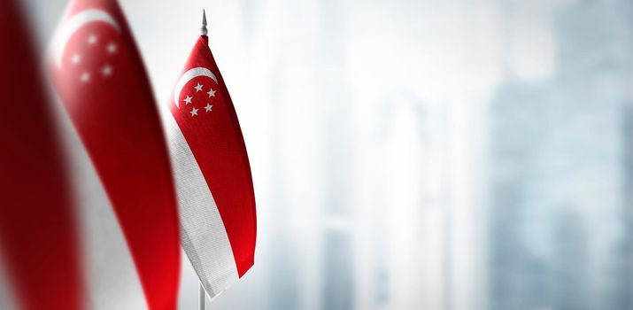 Small flags of Singapore on a blurry background of the city.