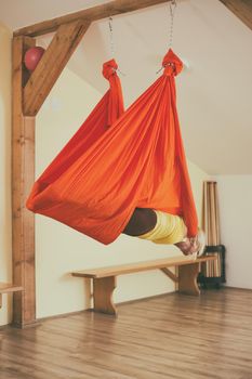 Woman doing aerial yoga in the fitness studio.Image is intentionally toned.