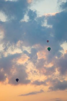 three hot air balloons in colorful sky with clouds during sunrise