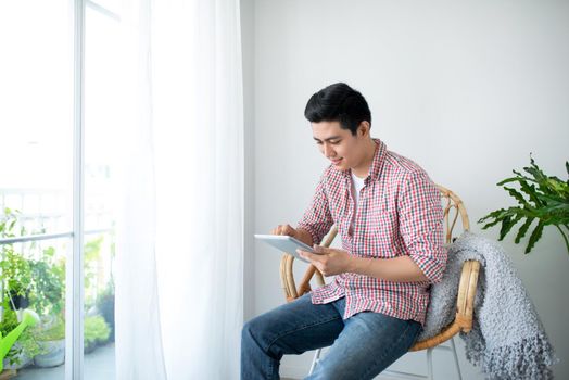 Portrait of a smiling man relaxing on chair new window using table and holding coffee cup.