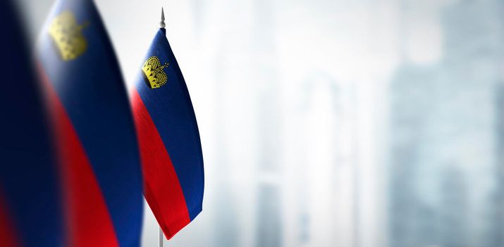 Small flags of Liechtenstein on a blurry background of the city.