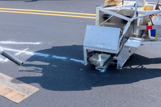 Road workers use hot-melt scribing machines to painting line on asphalt road surface in the city