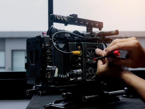 Technician using a screwdriver to changing the cooling fan of the movie camera.