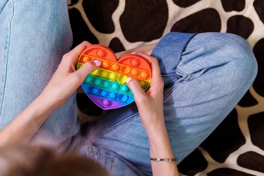 A girl plays with a silicone POP IT toy. New trendy silicone toy.