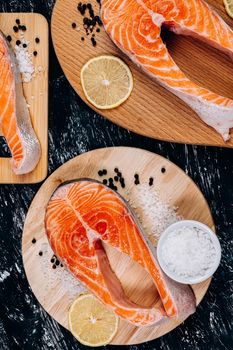 Fresh raw salmon fish steak with spices on ice over dark stone background.