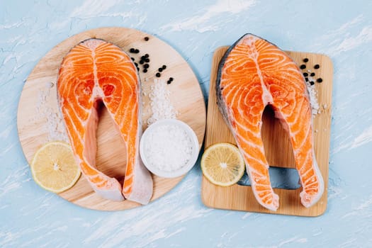 Fresh raw salmon red fish with spices, lemon, pepper on stone background. Top view, flat lay