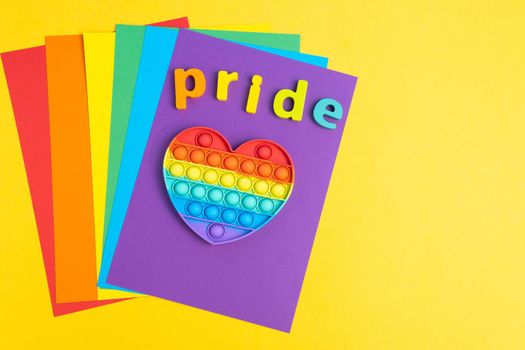 Text Pride Month LGBTQ with rainbow wooden letters. Pop it toy