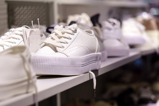 Sports fashion. Close-up of white fashionable sneakers on the store shelf. Selective focus.