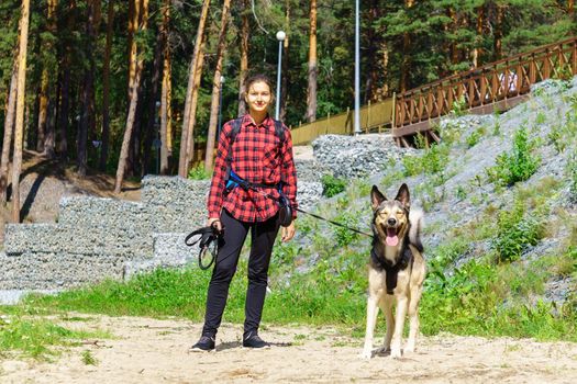 Young girl in a red shirt. The girl with the dog. Walk with animal in the forest