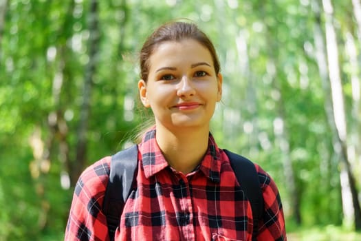 Portrait of a young smiling attractive girl. Selective focus. Green background of nature