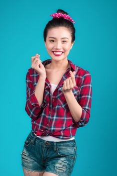 Smiling lovely asian woman dressed in pin-up style dress over blue.