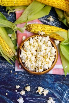 Fresh corn and popcorn on cobs on black background. Vertical photo