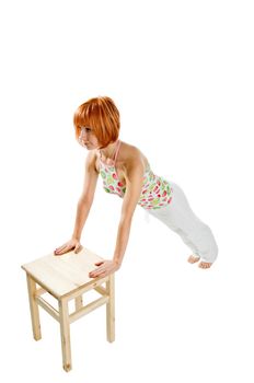 Red haired girl performing fitness exercises on white background