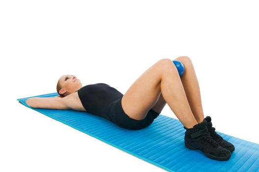 Beautiful fit red girl practicing pilates or callanetics with ball and blue yoga mat