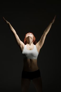 Fit red woman performing static power exercise in the spotlight