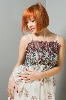 Portrait of beautiful red woman wearing long dress posing at the studio