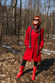 Beautiful girl wearing red coat and boots walking in the early spring