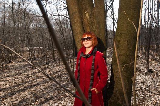 Beautiful girl wearing red coat and boots walking in the early spring