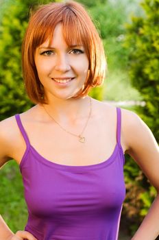 Beautiful healthy-looking red woman posing outdoors in a green park