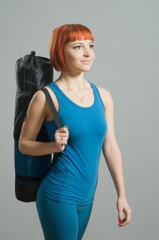 Red-haired fitness girl with yoga mat at the gym