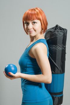 Red-haired fitness girl with yoga mat at the gym