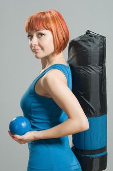 Red-haired fitness girl with yoga mat at the gym