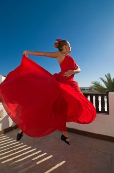 Attractive flamenco dancer wearing traditional red dress with flower in her hair