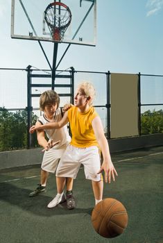 Two teenagers playing basketball at the street playground