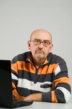 Mature man sitting at the table with laptop