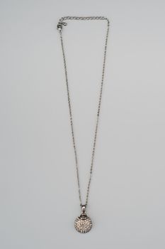 Silver necklace with pendant shot on gray background