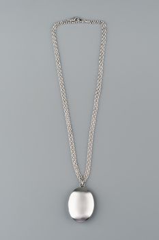 Silver necklace with pendant shot on gray background