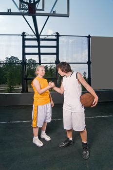 Two teenagers exchanging friendly handshake after streetball match