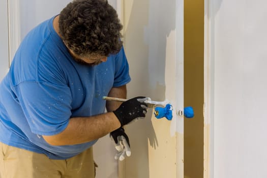 Contractor master processes painter painting wooden doors with using paintbrush in a house