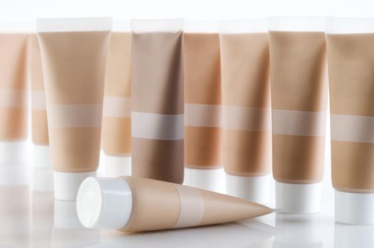 Many cosmetic tubes with creams standing on reflective background
