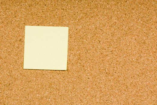 Blank sticky note on a cork bulletin board
