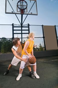 Two teenagers playing streetball with boy defending against girl