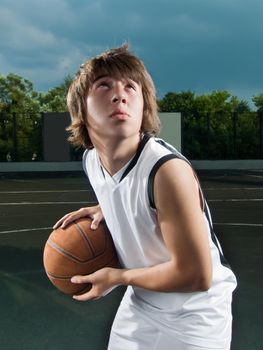 Cool asian boy in the middle of streetball match ready to shoot the ball