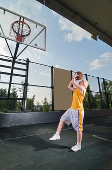 Teenage girl shooting basketball at the street playground